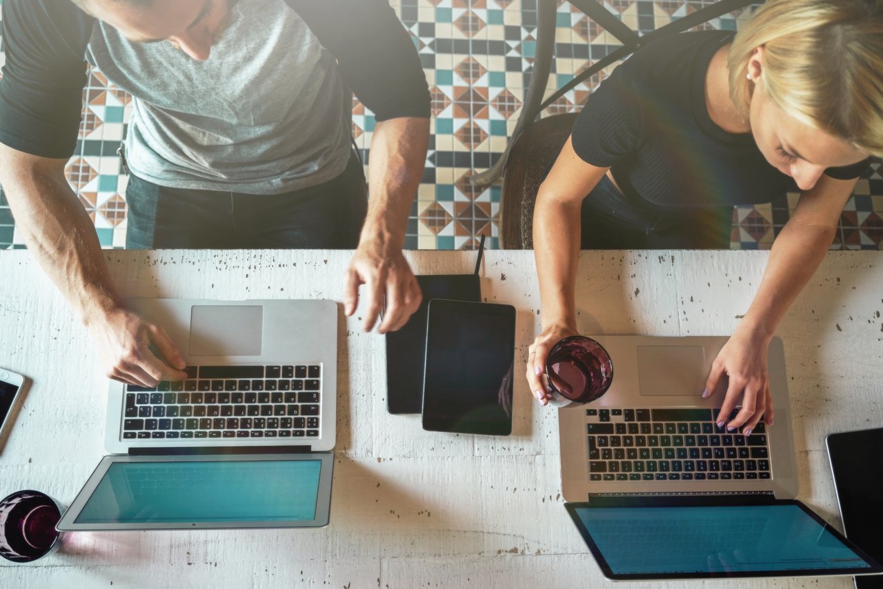 Two People Sitting Side by Side on Laptops Two People Sitting Side by Side on Laptops