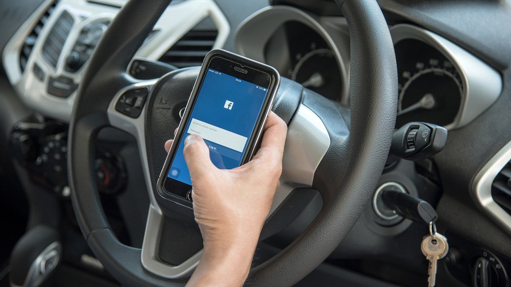 Facebook app on smartphone in a parked car Facebook app on smartphone in a parked car