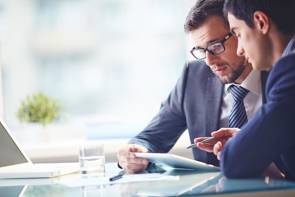 two business men in suits talking in front of laptop two business men in suits talking in front of laptop
