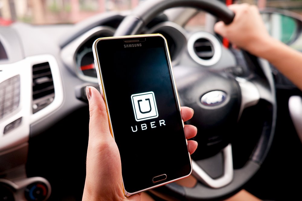 Woman Holding phone with Uber App Woman Holding phone with Uber App